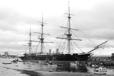 Boats moored at harbor against sky