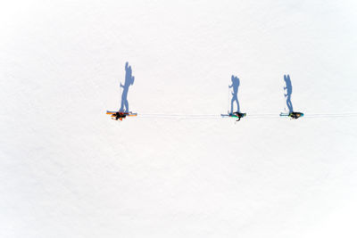 Directly above view of people skiing on snow during sunny day