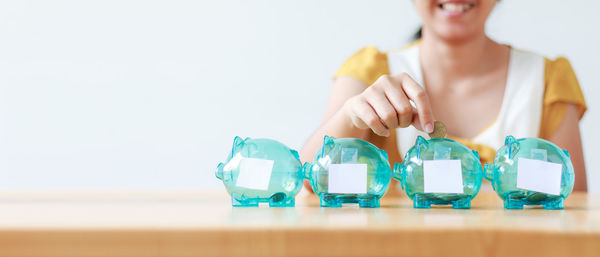 Midsection of woman putting coin in piggy bank