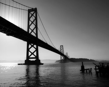 Silhouette of suspension bridge over sea