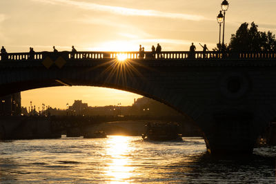 Silhouette of bridge over river during sunset. bridge pont au change in paris, france.