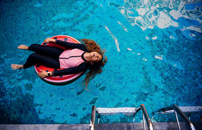 High angle view of girl floating on inflatable ring in swimming pool