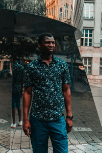 Young man standing on footpath in city