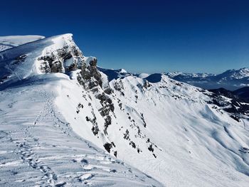 Scenic view of snowcapped mountains against clear blue sky