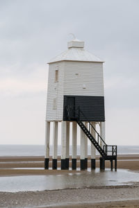 Built structure lighthouse on beach against sky