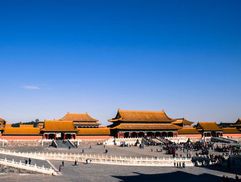 Group of people in front of building against blue sky
