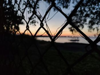 Close-up of silhouette fence on field against sky during sunset