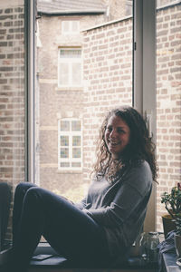 Young woman sitting in window sill