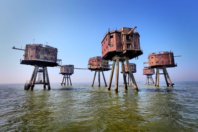 Lifeguard hut in sea against clear blue sky