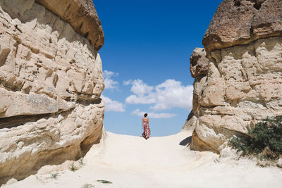 Rear view of woman standing on sand against sky