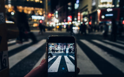 Close-up of person photographing in city at night