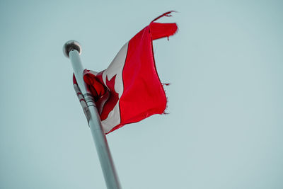 Low angle view of red flag against clear sky