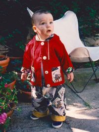 Full length of cute boy standing by potted plants in yard