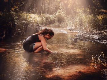 Side view of girl crouching in stream