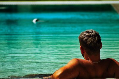 Rear view of shirtless man looking at sea