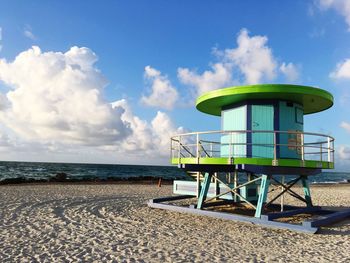 Lifeguard hut on beach against cloudy sky