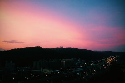 Illuminated cityscape against sky during sunset