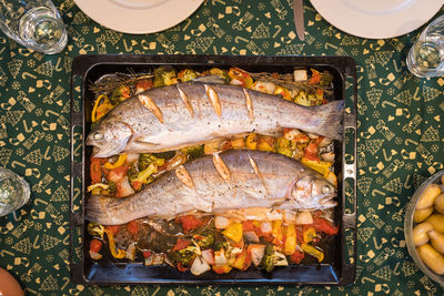Directly above shot of fish with vegetables in tray on table