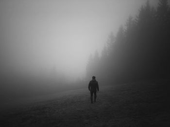 Rear view of man walking on road against clear sky