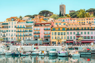 Boats moored at harbor against buildings in city