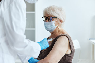 Doctor vaccinating senior woman at hospital