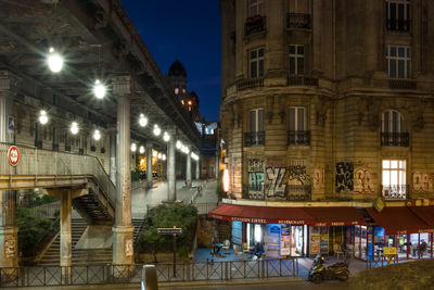 Illuminated street amidst buildings in city at night