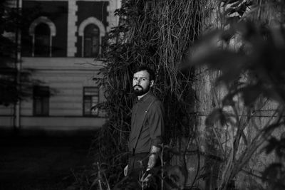 Portrait of young man standing by roots at night