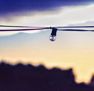 Low angle view of lighting equipment hanging against sky