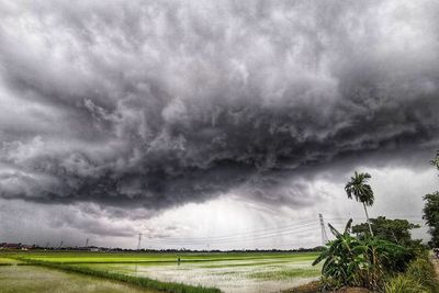 Scenic view of field against storm clouds