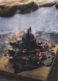 High angle view of tea pot on burning firewood at campsite