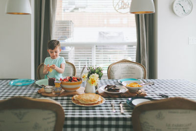 Boy having breakfast while sitting on table at home
