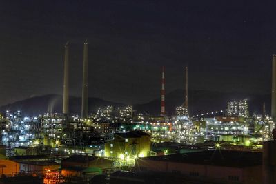 Illuminated factory against sky at night