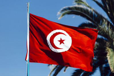 Low angle view of tunisian flag fluttering against clear sky