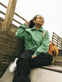 Smiling young woman looking away while sitting on steps