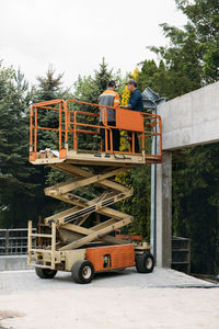 Scissor lift platform with workers on a construction site. building concreate house with mobile