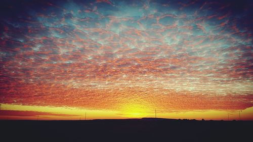 Silhouette landscape against dramatic sky during sunset