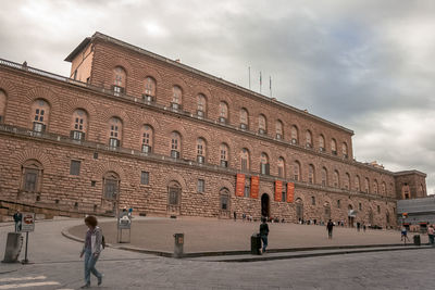 People walking on historical building against sky