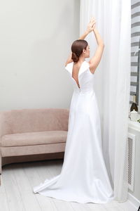 Full length portrait of unrecognizable brunette bride in  wedding dress posing with arms raised