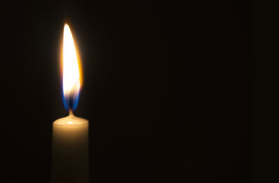 Close-up of lit candle against black background