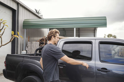 Carpenter entering pick-up truck outside workshop