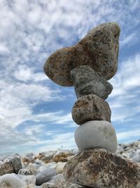 Low angle view of stone stack on beach against sky