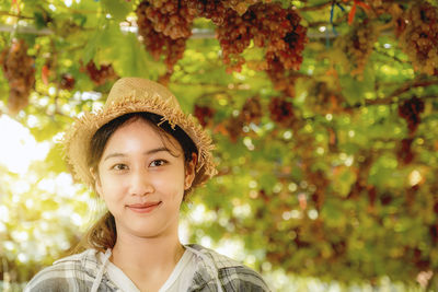 Portrait of smiling young woman against trees