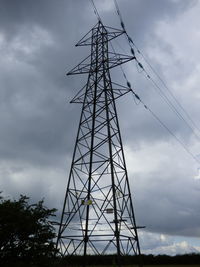 Low angle view of silhouette electricity pylon against sky