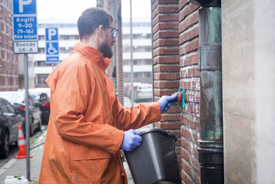 Man cleaning graffiti from wall