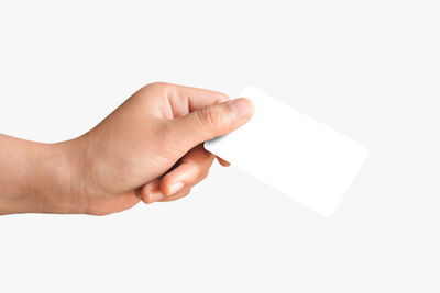 Close-up of hand holding paper against white background