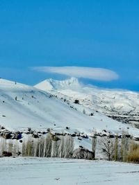 Snow covered landscape against blue sky