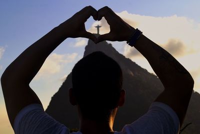 Man making heart shape against christ the redeemer