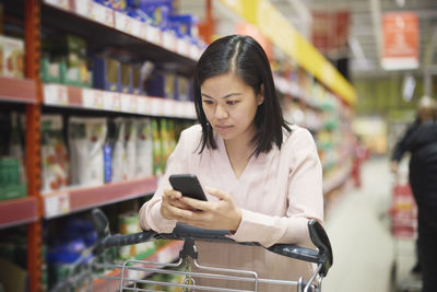 Woman looking at prices during inflation while doing shopping in supermarket