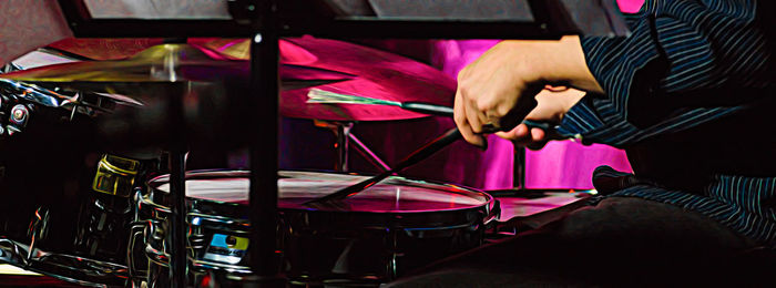 Midsection of drummer playing drums at concert