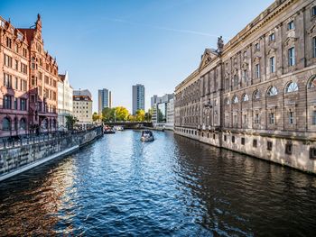 Canal amidst buildings in city against sky